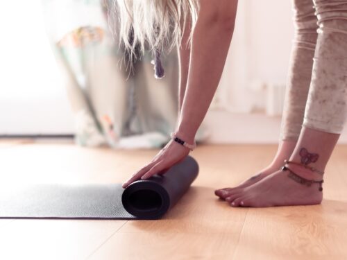 Close up of a woman rolling a yoga mat open.